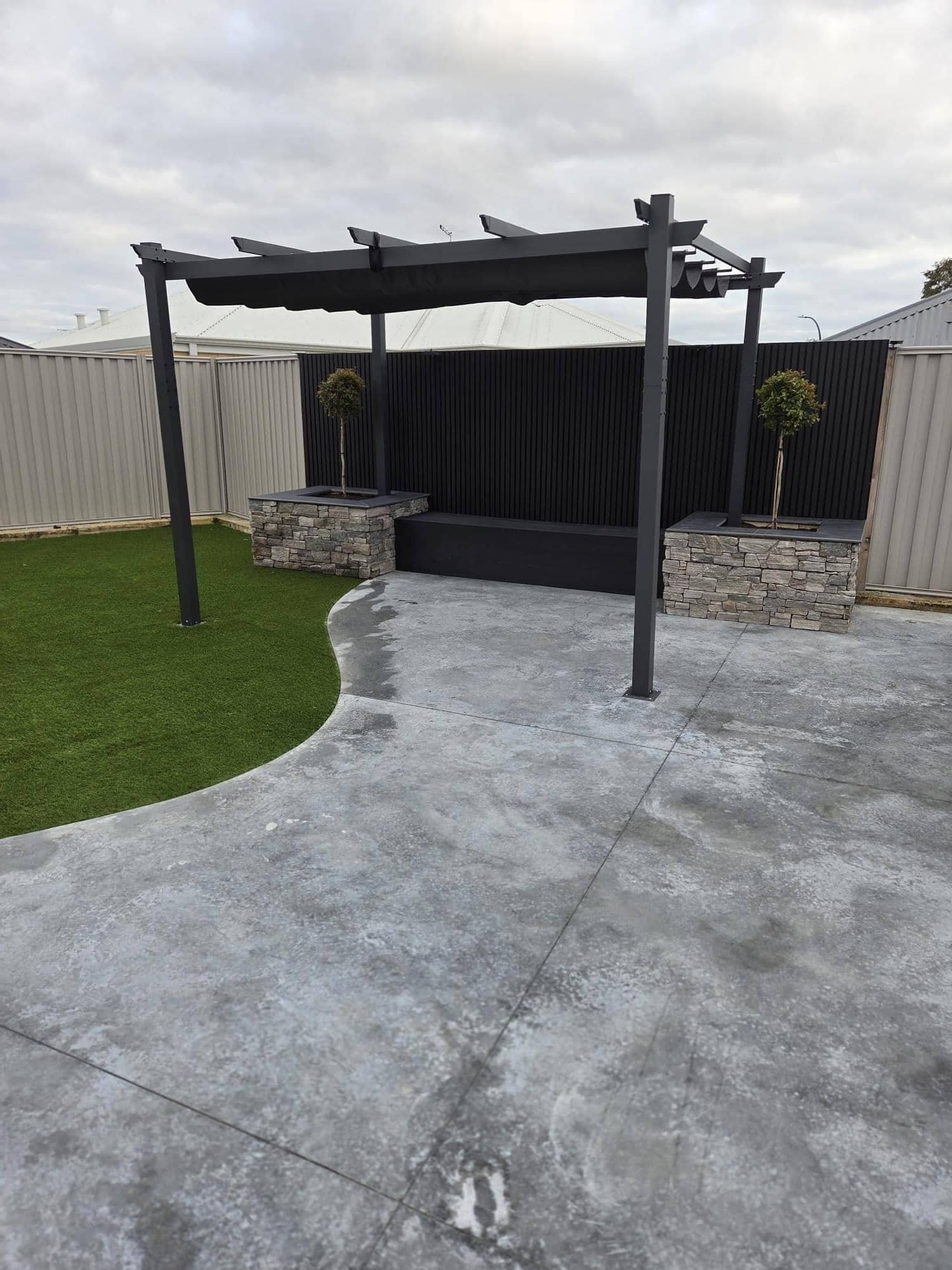 Modern backyard with pergola, stone planters and patio
