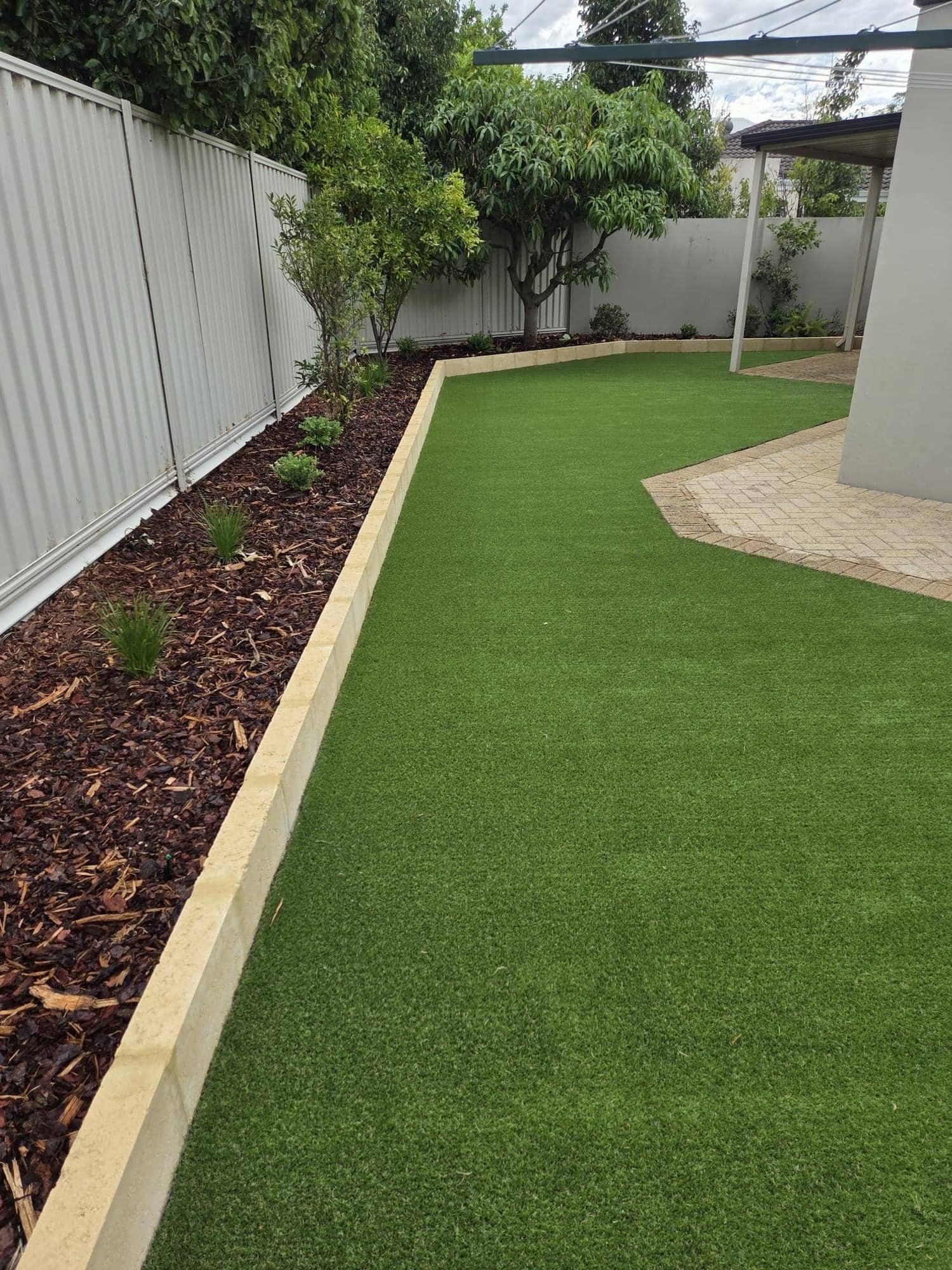 Backyard synthetic turf with mulch garden bed