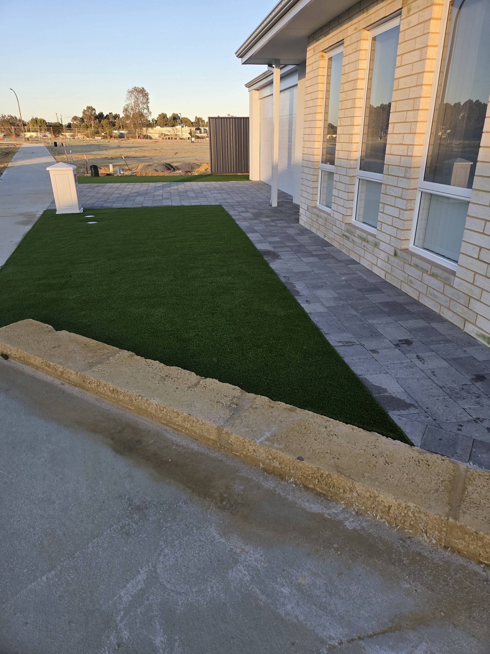 Front yard turf, charcoal paving and limestone wall